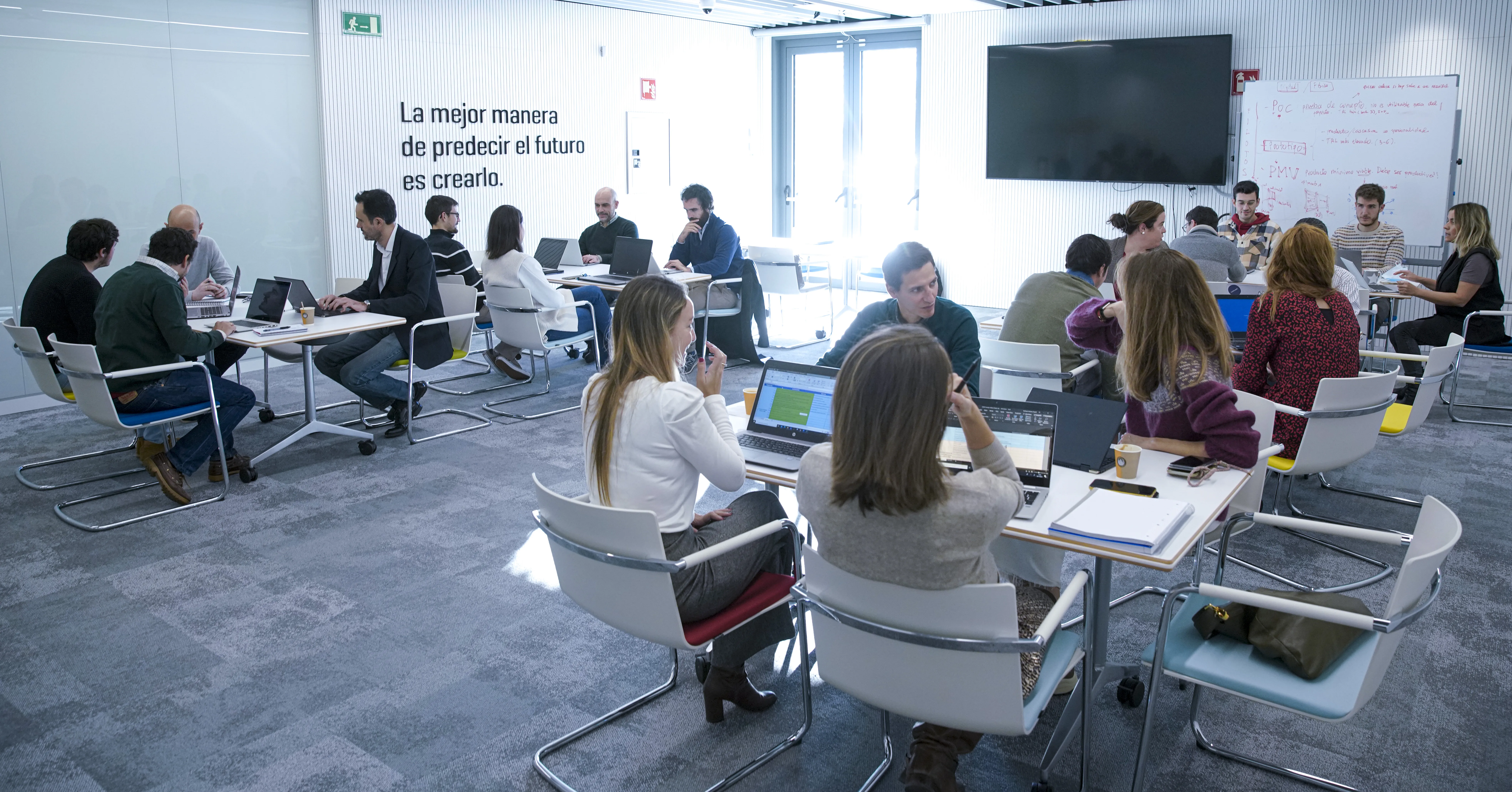 Personas sentadas en mesas grupales en una oficina