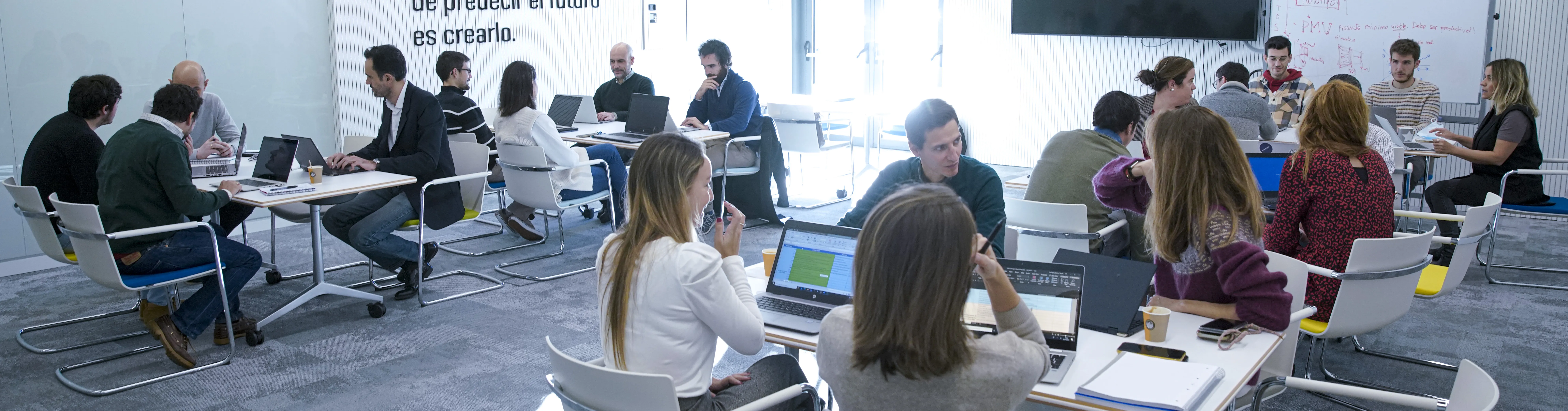 Personas sentadas en mesas grupales en una oficina